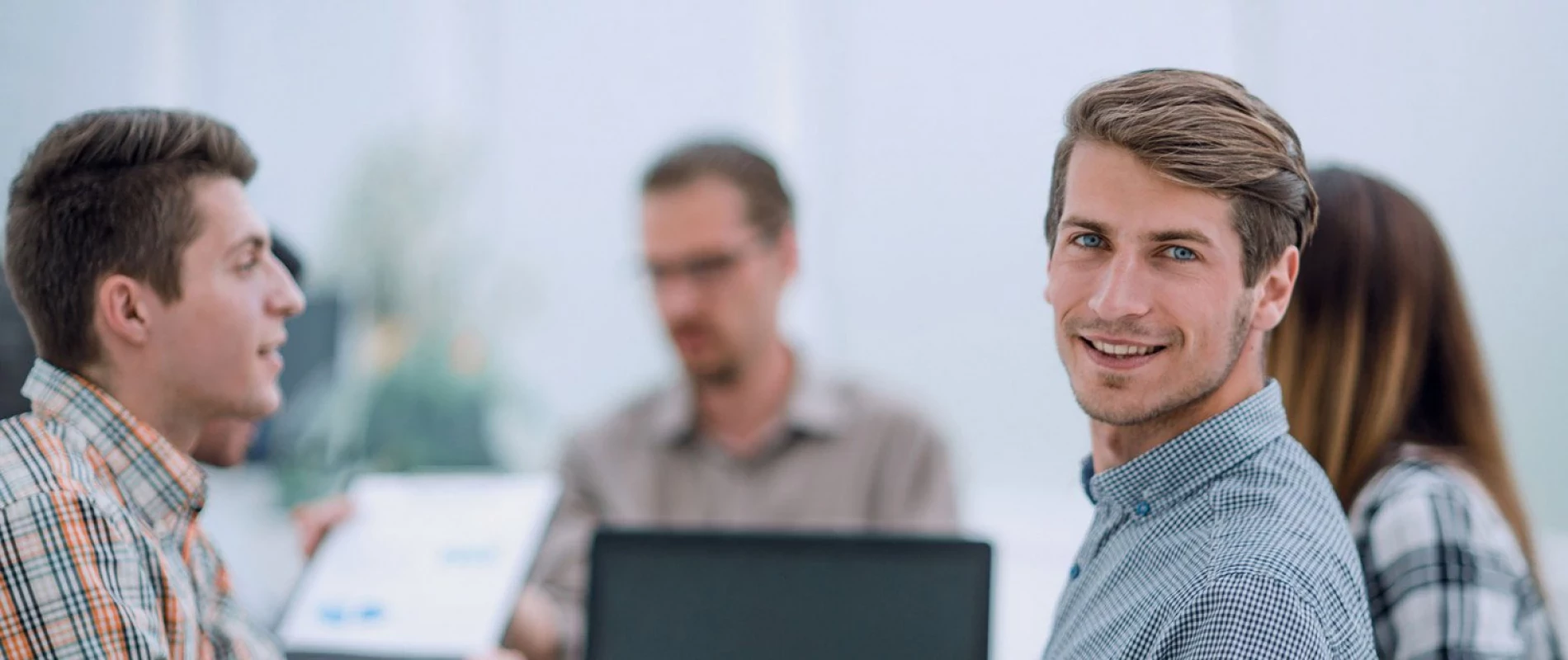 Junger Mann bei einem Meeting schaut in die Kamera, Copyright: ASDF - stock.adobe.com