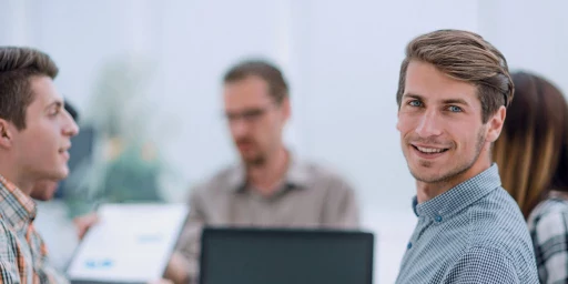 Junger Mann bei einem Meeting schaut in die Kamera, Copyright: ASDF - stock.adobe.com