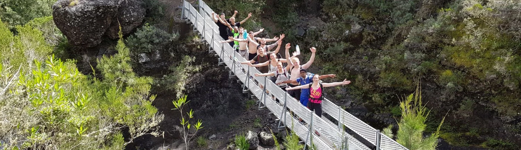 Junge Menschen stehen auf einer Hängebrücke in tropischer Landschaft, Copyright: BZB