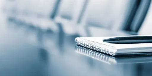 BZB Seminare Lehrgänge Notizblock mit einem Stift in einem leeren Seminarraum, Copyright: Mariakray - stock.adobe.com